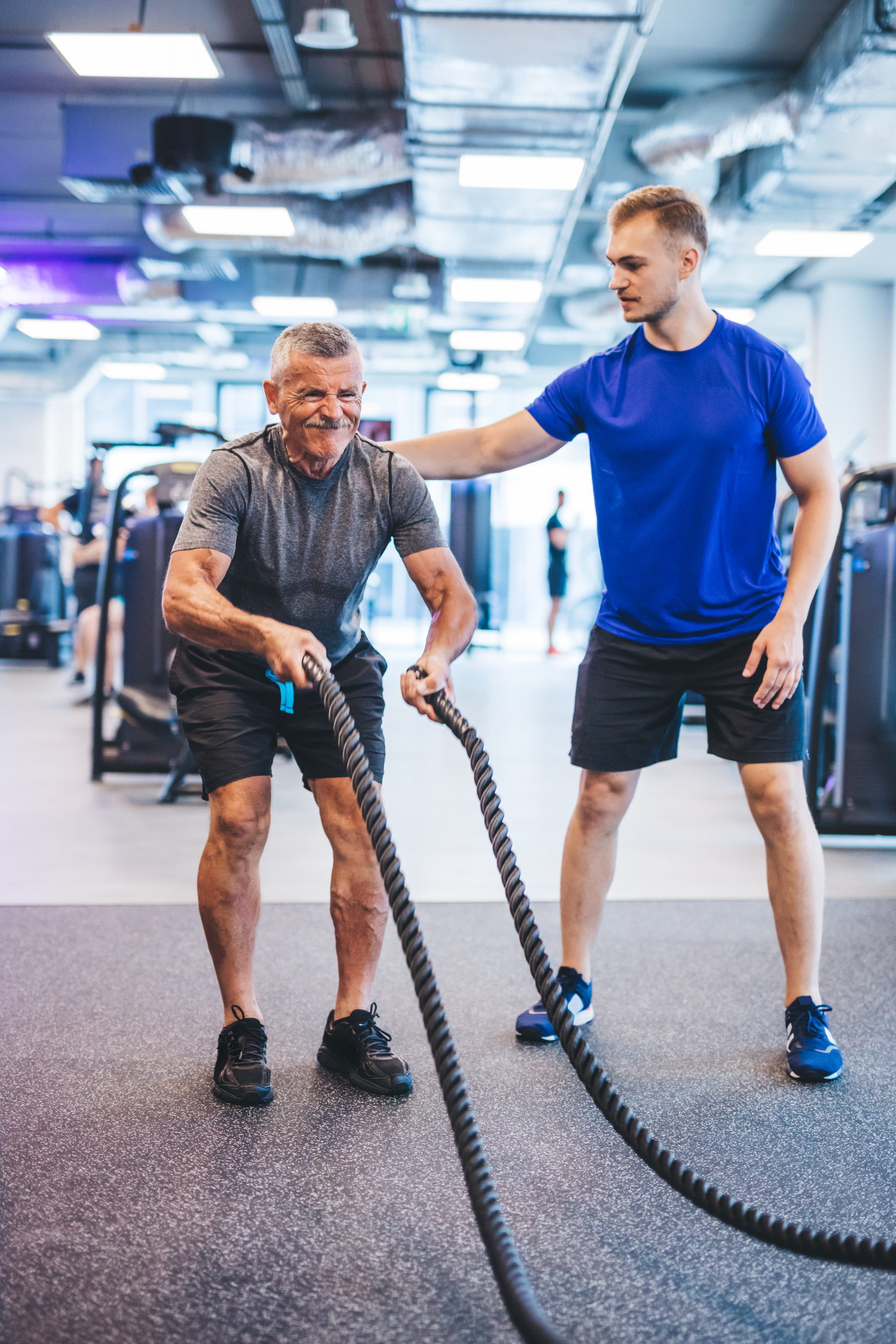 Senior Man Exercising at the Gym with Gym Instructor.
